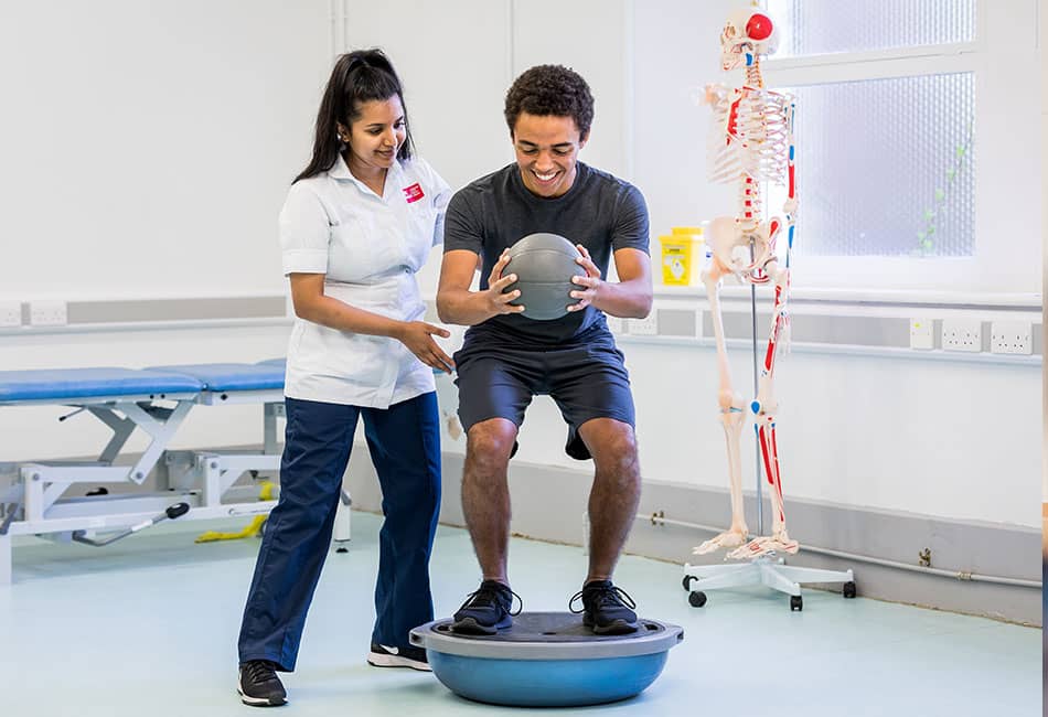 A physiotherapy student supporting a patient with physical exercises.